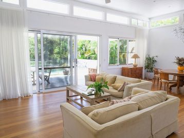 Bright living room with beige sofas, wooden floor, and large sliding glass doors.