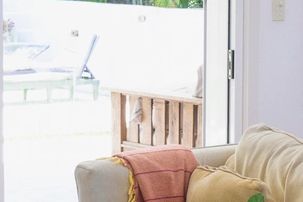 Bright residential living room featuring large windows, glass patio doors, hardwood floors, and natural sunlight that will be protected with a durable UV film that is energy efficient.