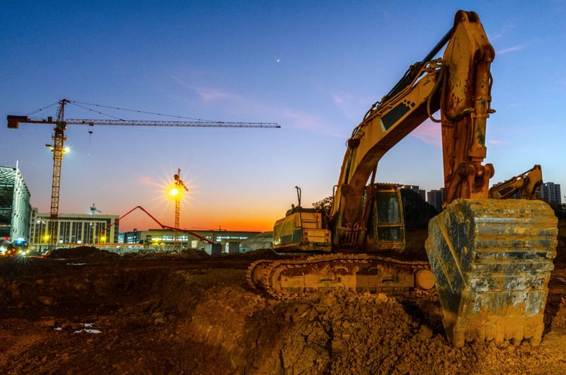 Construction sites at dusk, excavators, cranes,