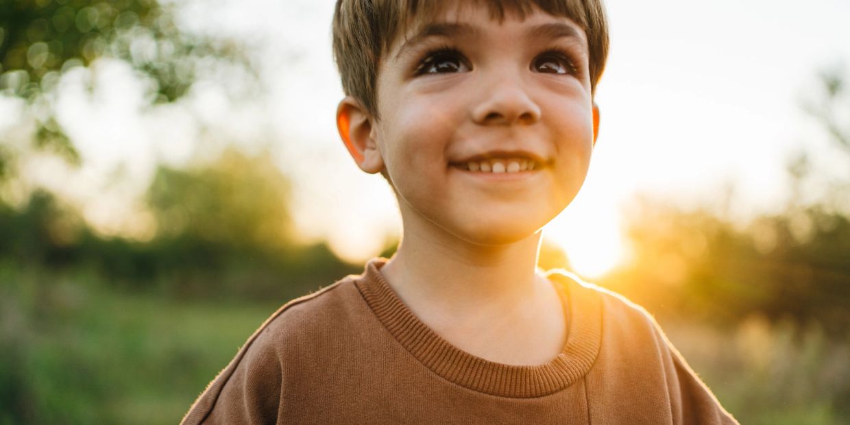 Smiling boy outdoors at sunset.