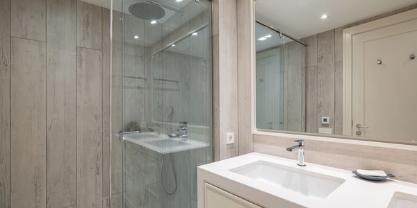 Modern bathroom with glass shower and wooden panel walls.
