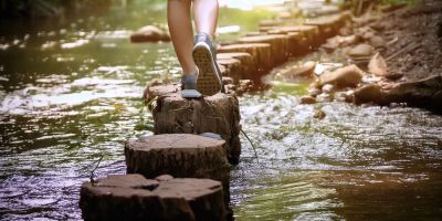Person walking on stepping stones across a stream.
