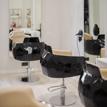 Modern black salon chairs with beige cushions in a clean, minimalist hair studio.