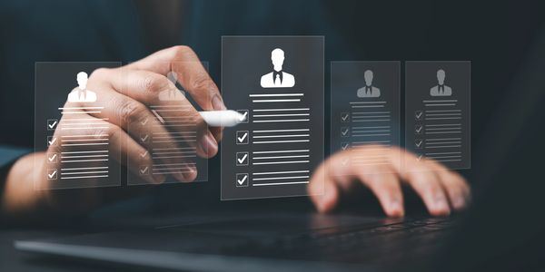 Person selecting a digital resume from multiple holographic profiles on a laptop.