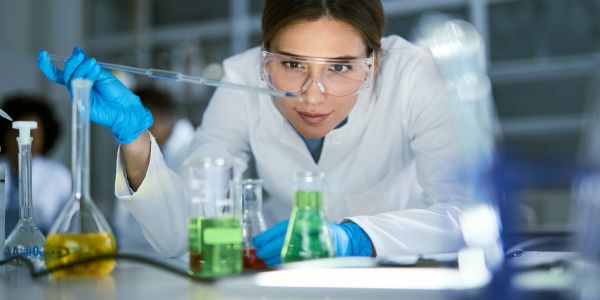 Female scientist working in lab with protective gear.