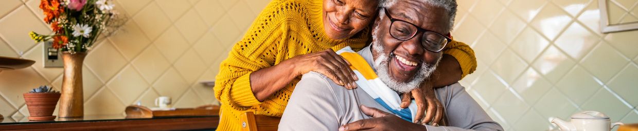 Elderly couple sharing a joyful embrace in a cozy kitchen.