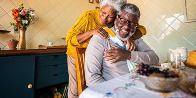 Elderly couple sharing a joyful embrace in a cozy kitchen.