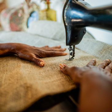 Hands guiding fabric through a sewing machine.
