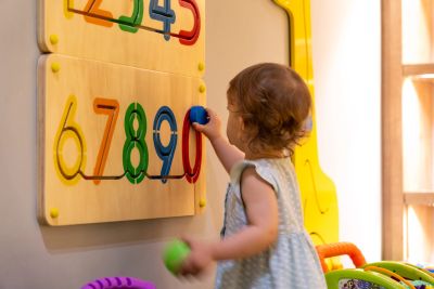 Toddler playing with a colorful number puzzle on the wall.