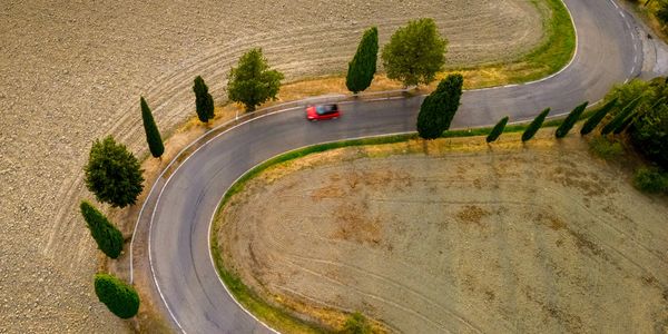 Winding road through rolling hills and vineyards in Tuscany, Italy, known for its stunning landscapes and rich cultural heritage.