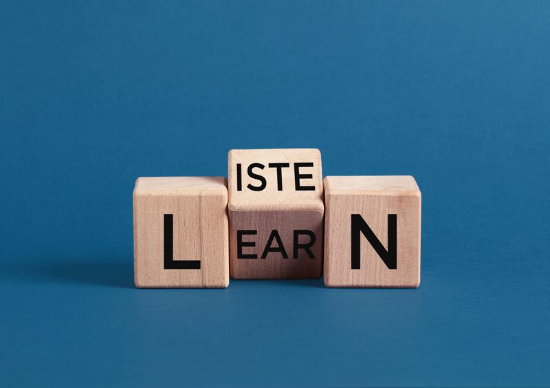 Wooden cubes spelling listen and learn, conveying the importance of active listening as a prerequisite for effective learning