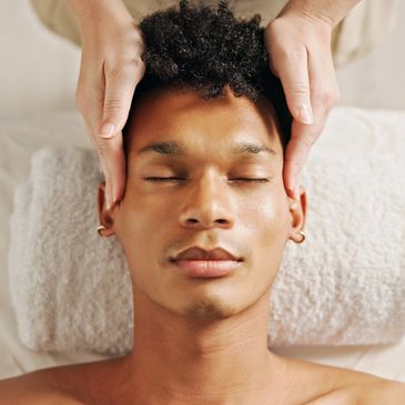 Man receiving a relaxing facial massage with eyes closed.