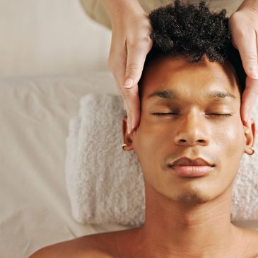 Man receiving a relaxing facial massage with eyes closed.