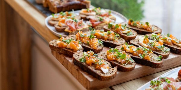 Slices of bread topped with diced vegetables and greens arranged on wooden boards.