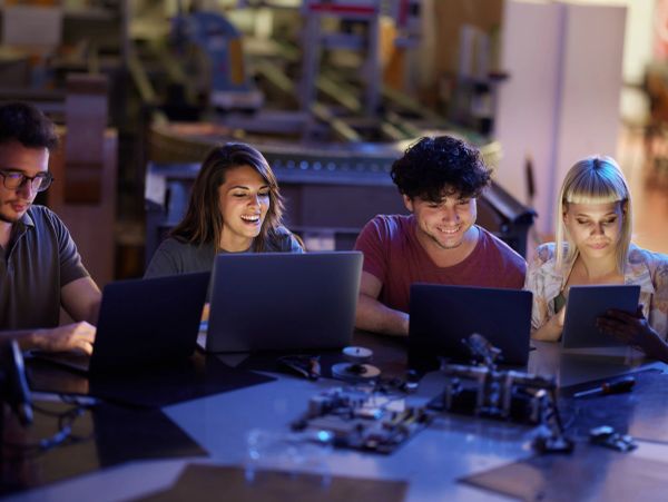 Group working on laptops and tablet in a tech workspace.