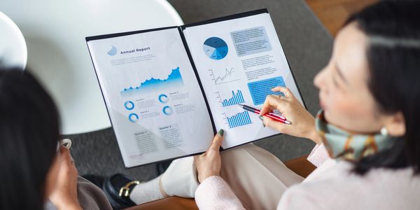 Two women reviewing an annual report with graphs and charts.