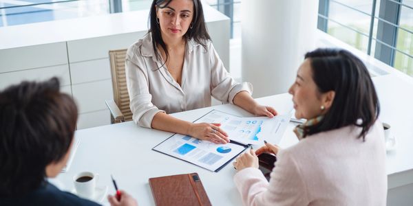 Three professionals discussing charts and reports in a modern office setting.