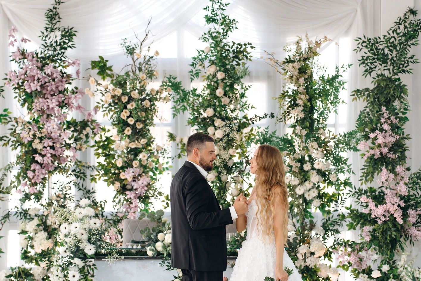 Bride and groom sharing a moment amidst lush floral wedding decor.