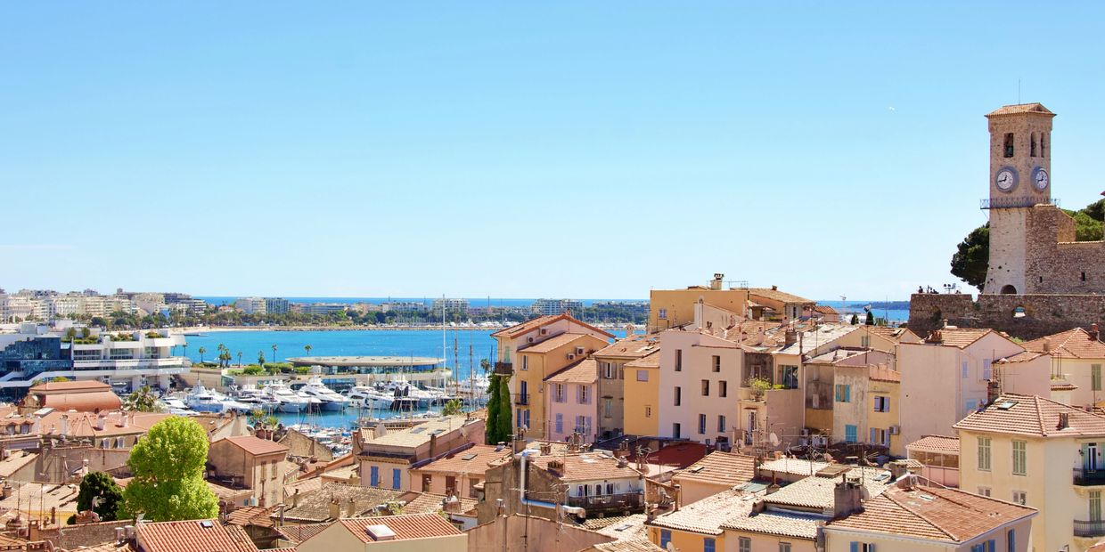 Coastal town with terracotta roofs, yachts, and a clock tower under a clear blue sky. Bachelor in Gastronomy, Gastronomy Degree, Swiss Hospitality Education