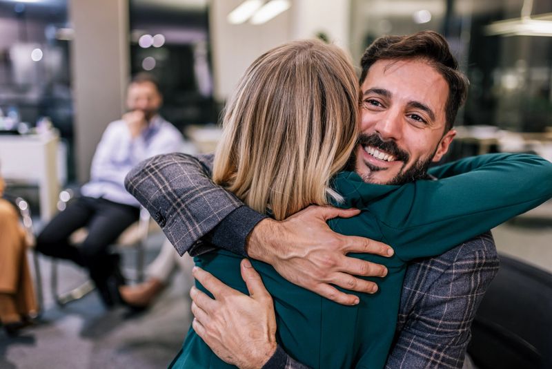 Business partners hugging on a group psychotherapy. Understanding each other's problems and meeting each other better.Psychotherapy training, business lecture, seminar or conference.