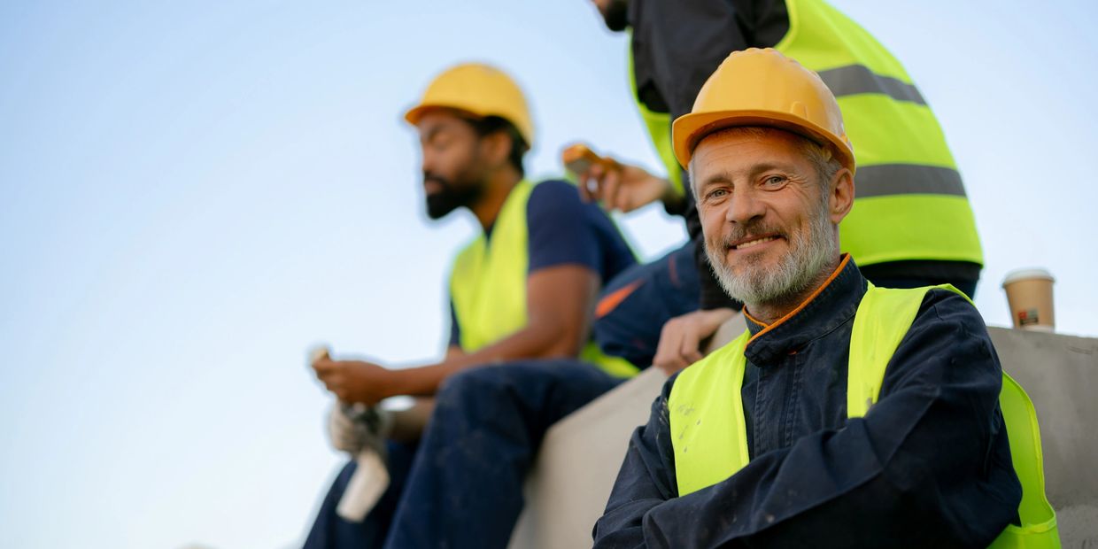 Construction workers taking a break, wearing safety helmets and vests.