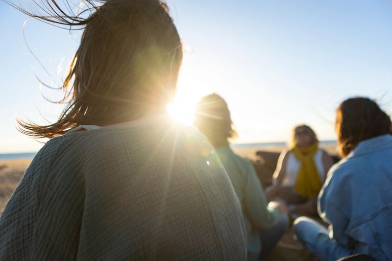 Group of women meditating together at the beach during a spiritual retreat at sunset