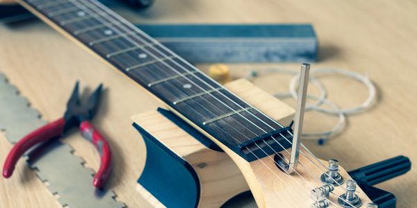 Electric guitar being repaired with tools on a workbench.