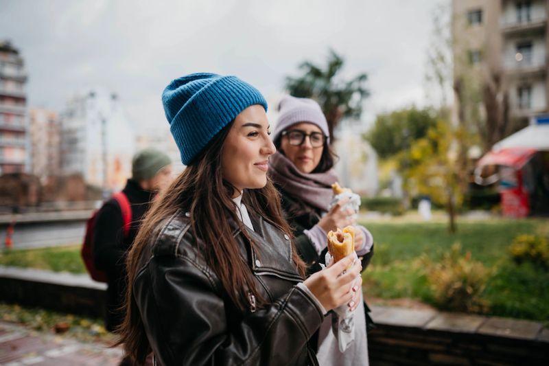 Young friends walking down the street while eating fast food