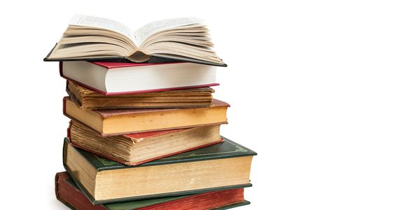 A stack of old books with one open on top.