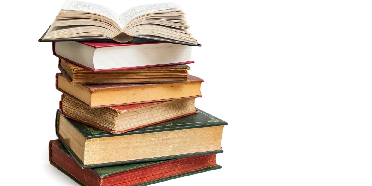 Stack of old and new books with one open book on top.