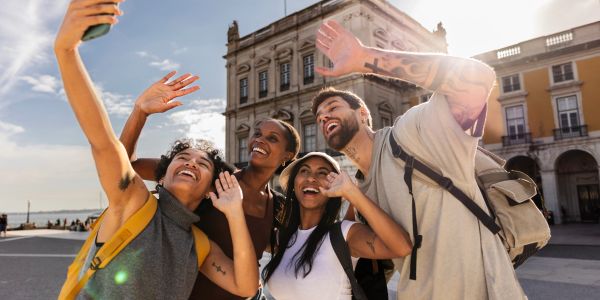 Group of friends taking a selfie outdoors on a sunny day.