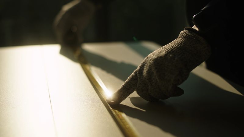 Close-up hand using measuring tape on furniture.