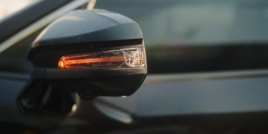 Close-up of a car's side mirror with a cracked turn signal light.