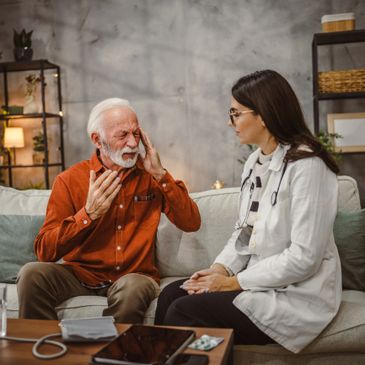 Elderly man consulting doctor about headache pain at home.