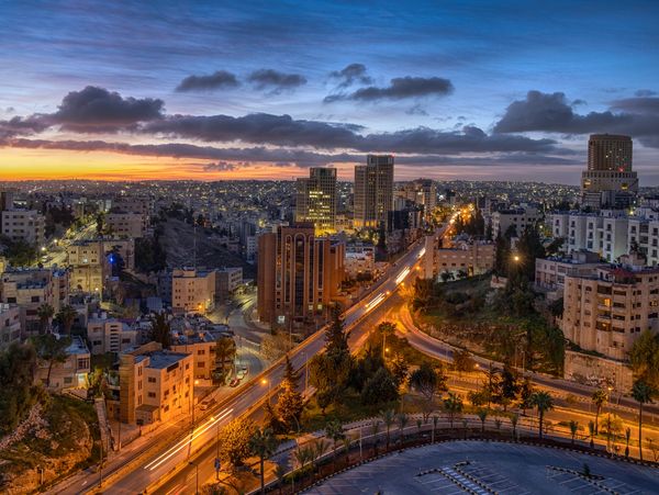 Cityscape at dusk with illuminated roads and buildings.