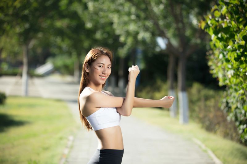 Asian woman stretching her arms in a park