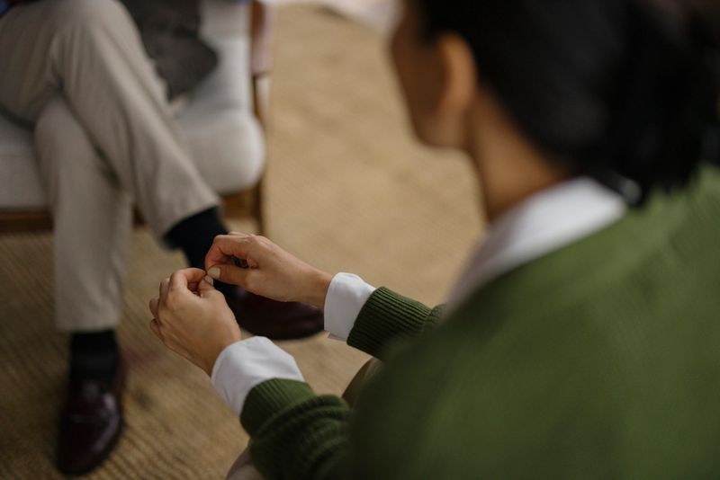 A professional counseling scenario emphasizing the interaction between client and therapist, showcasing hands expressing non-verbal communication and the seriousness of the session focused on emotional and psychological support.