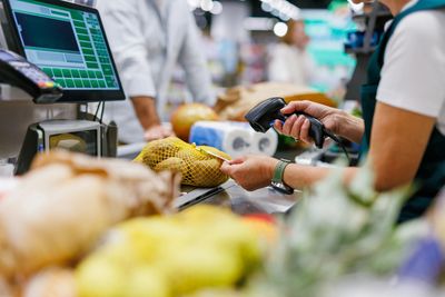 Cashier scanning groceries at the checkout counter in a supermarket.