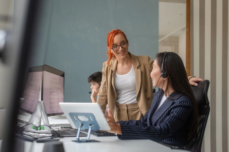 Teamwork in a professional environment as coworkers engage in discussions and provide support. The modern office setup highlights the use of technology and effective communication between employees to ensure productive results.