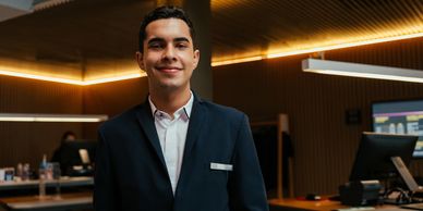 Smiling young man in a suit at a modern reception desk.