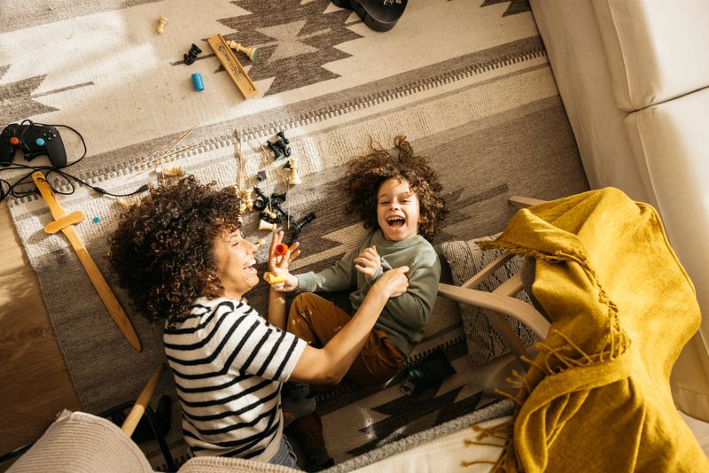 A joyful moment where a mother and son share laughter and playtime in their cozy living room, surrounded by toys and a warm atmosphere.