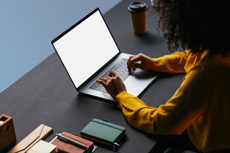Businesswoman typing on a laptop with a blank screen, offering copy space for design and customization in a modern office setting