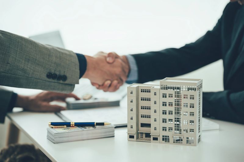 Two businessmen holding hands at the table represents a successful real estate deal. Close up of handshake between real estate agent and new home owner. Close-up photo.