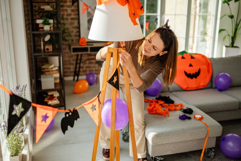 A cheerful woman enhances the home ambiance by arranging Halloween decorations for a festive celebration.