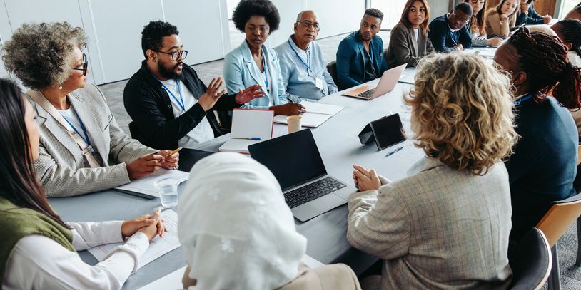 Diverse group engaged in a serious meeting around a conference table.