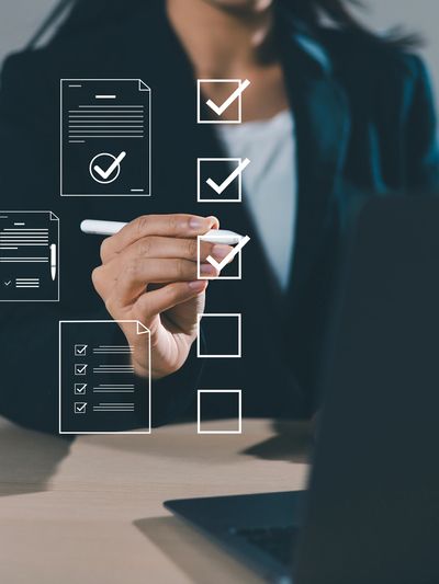 Person in business attire marking checkboxes on a virtual checklist.