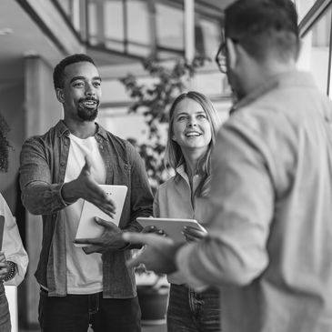 Diverse colleagues greeting each other with smiles and handshakes in a modern office.