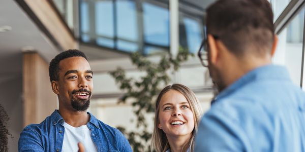 Young professionals greeting each other in a modern office setting.