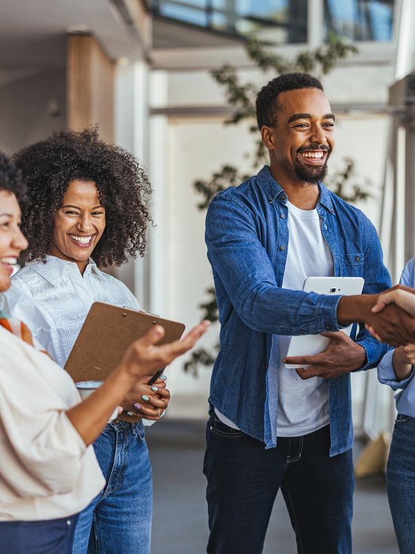 Happy colleagues shaking hands and laughing in a modern office.