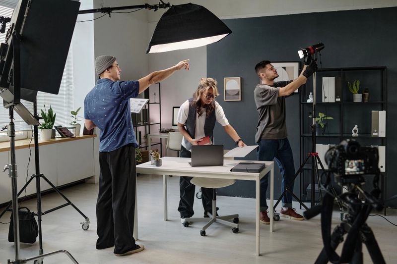 Team of creating videographers and their female assistant preparing studio for shooting